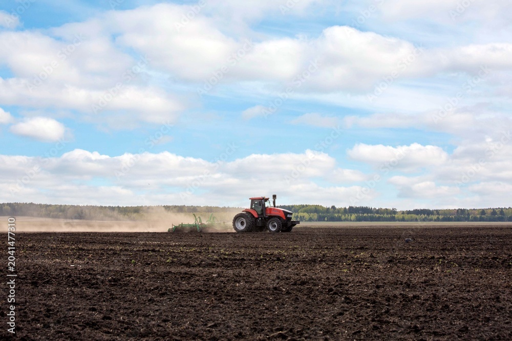 Obraz premium A tractor plowing a field in spring. Agricultural work, farming.