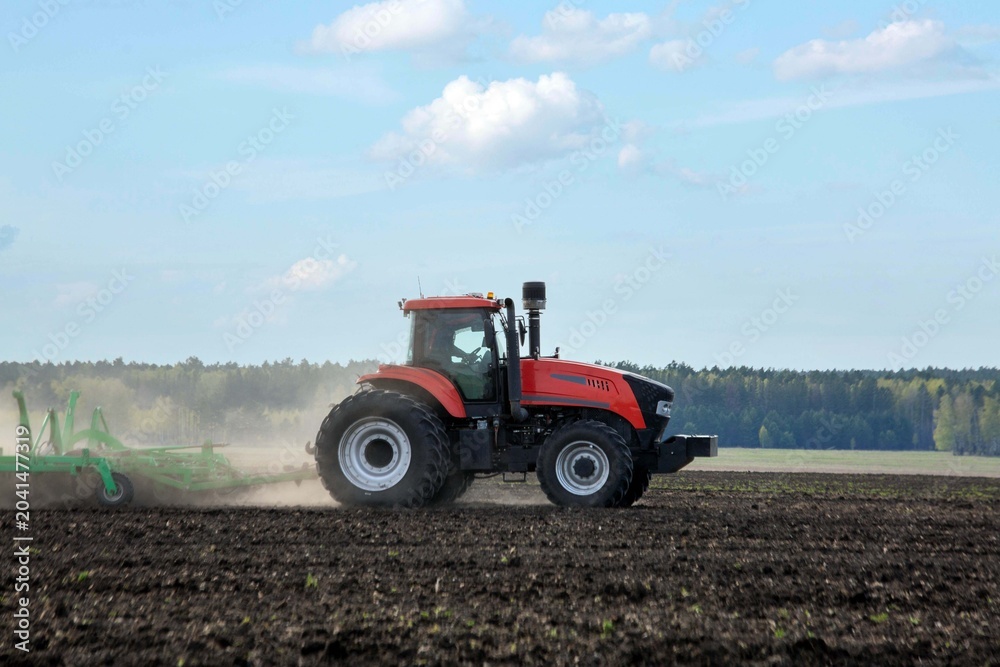 Obraz premium A tractor working in a field in spring. Agriculture, farming.