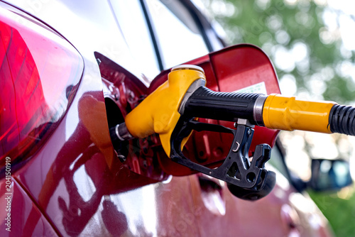 Konstfotografi Close-Up View of a Fuel Pump Nozzle Refueling a Red Car at a Gas Station, Highli