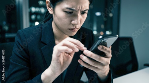 Woman looking at phone with confused expression.