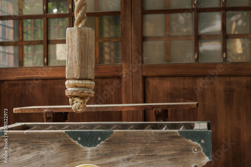 Fotografía Close‑up of saisen box and suzuo rope's thick wooden handle at Shinto shrine, set against traditional sliding doors with lattice‑inlay windows softly lit by natural light