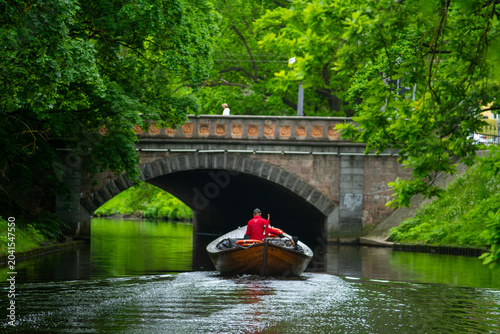 Foto small boat passing under stone bridge on canal in city park
