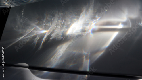 Foto Light shines through a transparent object, casting reflective patterns on a flat surface