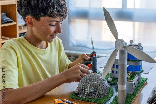 Teenager using a glue gun to make a project with recycled materials