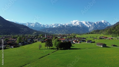 Quadro su tela Alpine town below snow-capped peaks