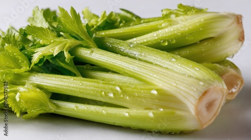 Freshly washed stalks of celery with glistening water droplets rest on a clean surface