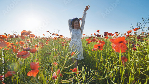 Fotografie Woman wearing flower crown stretching amid blooming poppy field, basking in gold