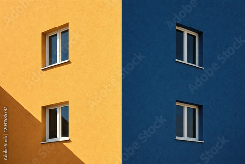 Abstract minimalist building facade combining blue and yellow walls with simple windows and strong geometric balance.