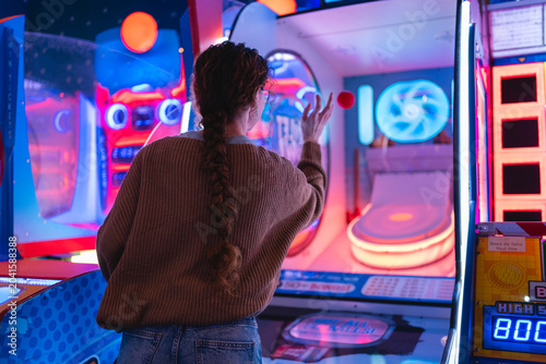 Fotografía Young woman having fun playing a game in a modern, colorful arcade