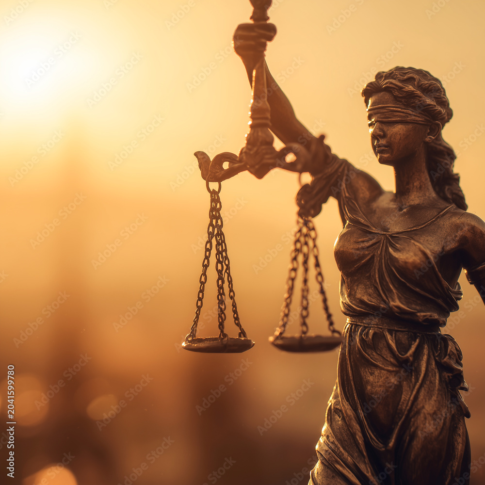Bronze statue of Lady Justice holding scales, blindfolded, against a dramatic warm sunset sky, symbolizing law, order, and judicial authority