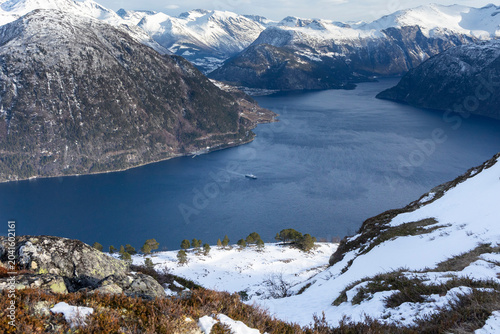 A beautiful winter day landscape from the Blahornet mountain towards fjord with a ferry crossing. A scenery in the Eidsdal hiking area, Geiranger Unesco World Heritage Site, Sunnmore region, Norway.