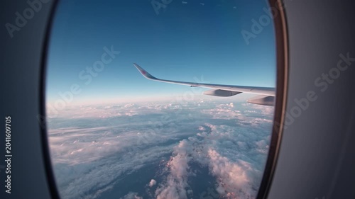 The airplane wing extends into a clear sky, framed by the window. Perfect for travel and aviation-related projects.