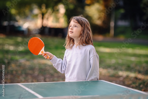 Quadro em tela Young girl playing table tennis outdoors concentrating