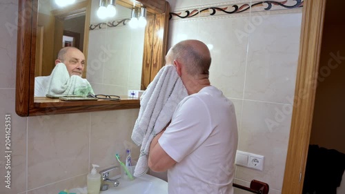 Senior Man Drying His Face With Towel During Morning Bathroom Grooming Routine  