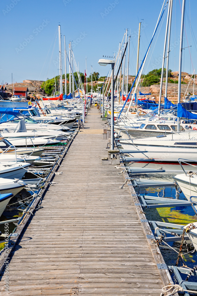 Obraz premium Marina with boats along wooden pier in Swedish coastal landscape