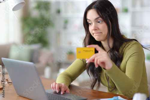 Foto Perplexed young student buying online using laptop and card