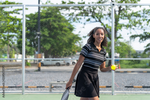 Young woman playing pickleball match on outdoor court. Athletic female player holding paddle racket waiting for ball during padel tennis game training session