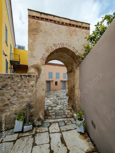 Weathered stone arch and restored Plaka courtyard in Athens, blending old masonry, narrow passage, and timeless neighborhood character.