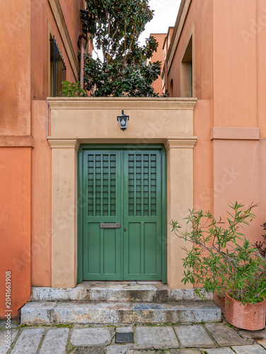 Historic entrance of a terracotta-colored house with a dark green door in the charming Plaka district, Athens.