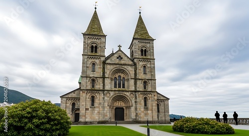 Historic Stone Church Standing Under Cloudy Sky in Landscaped Mountain Setting
