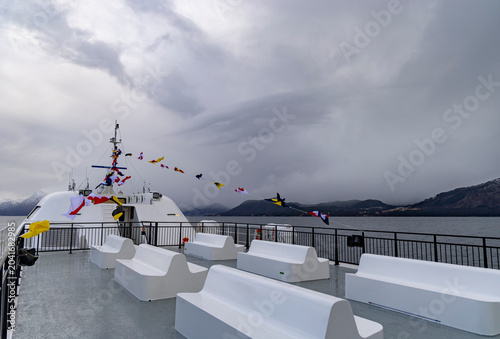 Bilde på lerret An empty upper deck of a tour ferry in fjords with nautical flags blowing in the wind
