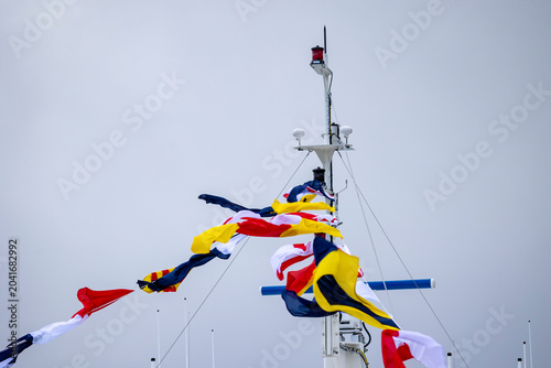 An empty upper deck of a tour ferry in fjords with nautical flags blowing in the wind. Winter scenery in Geirangerfjord, Sunnmore region, Norway.