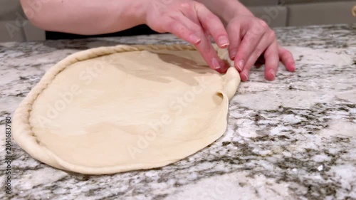 Hands folding dough edge on floured kitchen surface