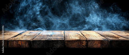 Textured wooden table surface with vibrant blue smoke rising on a black background, creating an atmospheric and dramatic setting