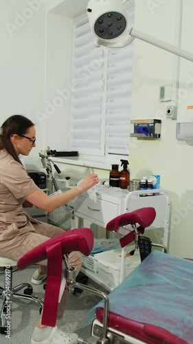 Gynecologist searches cabinet for examination tool in clinic room. Doctor selects needed instrument preparing equipment for patient check