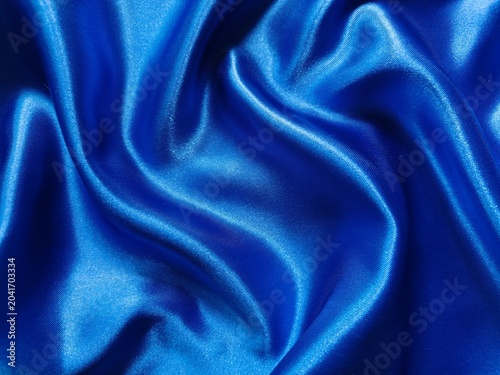 Luxurious royal blue satin fabric shimmers with elegant folds, creating a rich and sophisticated abstract texture.
