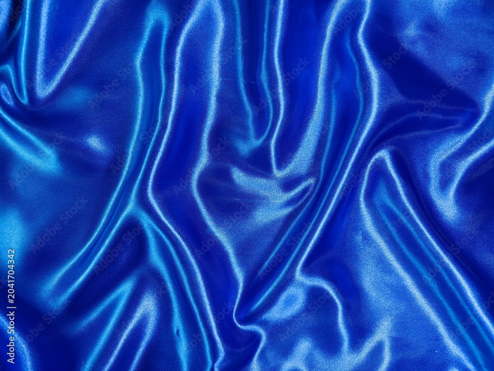 Fototapeta premium Luxurious royal blue satin fabric shimmers with elegant folds, creating a rich and sophisticated abstract texture.