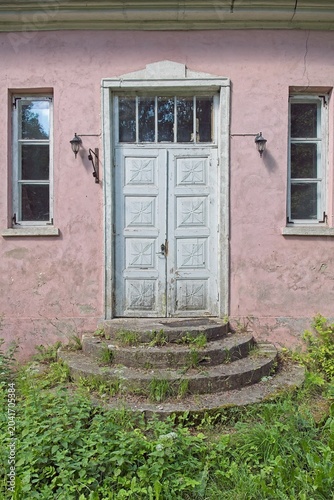 Schilderij op canvas Weathered, old light blue door on a pink building
