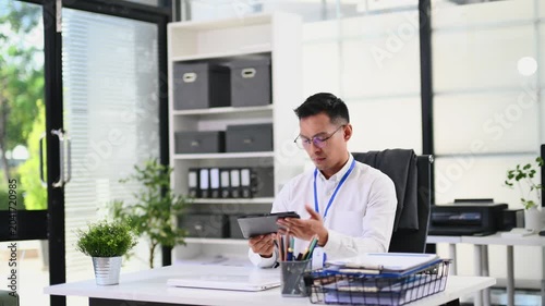 Asian businessman packing personal belongings into a cardboard box, clearing his office desk after resignation