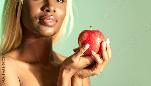 Young Blonde Woman Holding Red Apple Against Soft Green Background