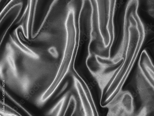 Luxurious black satin fabric flows with elegant folds, creating a sleek and sophisticated texture full of depth and shine.