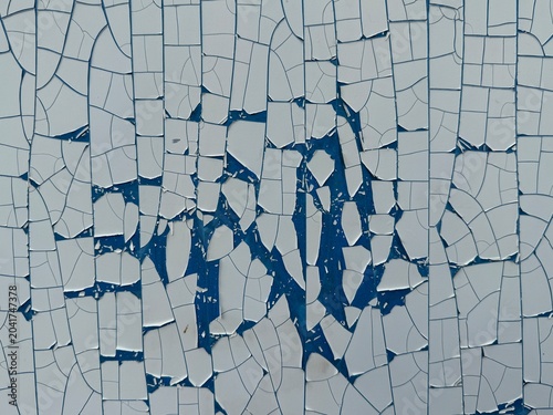Texture background of cracked and peeling white paint on a blue surface. Abstract weathered background showing signs of age and decay.