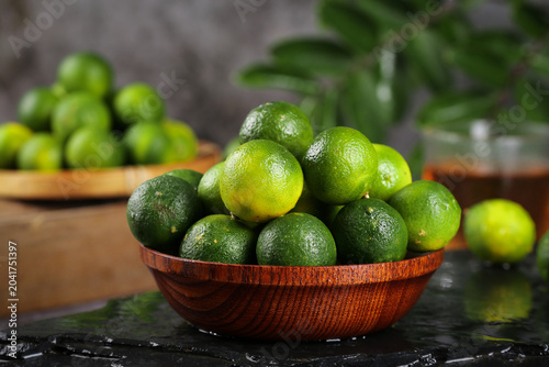 Fotografie Fresh Green Limes from Hainan in Wooden Bowl - Tropical Citrus Fruit Display