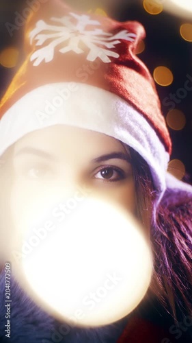 Christmas cute woman with Santa hat looking at the camera surrounded with lights