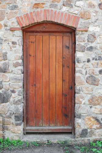 Old wooden door in masonry wall front view, architecture detail