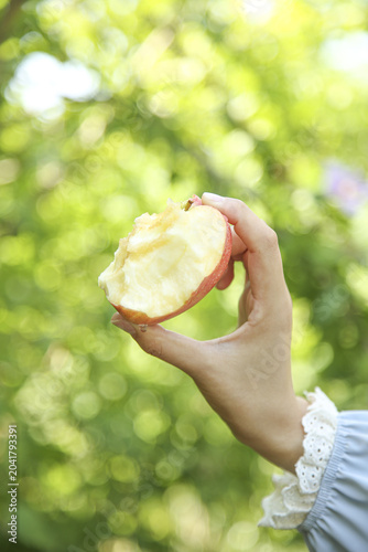 Fotografie Fresh Red Apple with Bite in Hand Against Green Nature Background