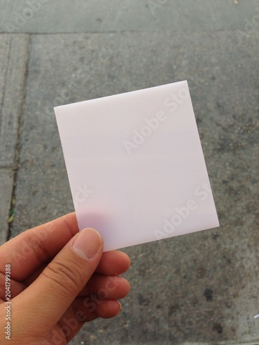 Hand Holding Blank Card Above Street