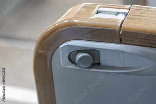 фотографія View of a recline or adjustment button under a wooden-textured armrest of a train seat