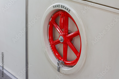Foto Close up of a red manual hand brake wheel system on a vintage train passenger carriage wall