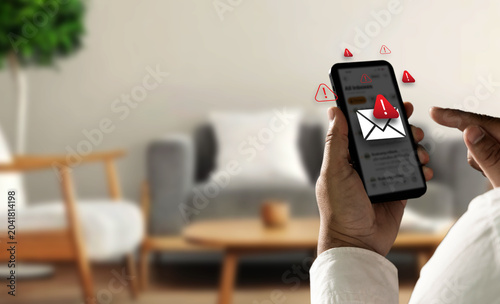 Obraz na plátne Person holding smartphone with spam warning icons and fake message alert interface, representing SMS phishing attack, mobile scam risk, online fraud prevention, and cyber security protection