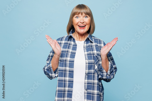 Bild auf Leinwand Elderly shocked surprised fun blonde woman 50s years old wear checkered shirt casual clothes spread hands look camera isolated on plain pastel light blue background studio portrait