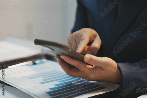 Obraz na plátně A corporate worker holding up a financial report spreadsheet over a desk clutter