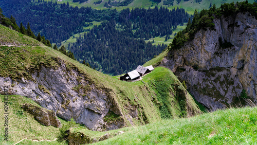 Mountain landscape with a small cabin on a hillside in a green valley