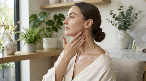 Serene woman embraces self-care, gently massaging nourishing neck serum for healthy, radiant and youthful skin.
