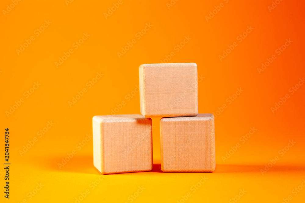 Obraz premium Wooden cubes isolated on orange background. Business and finance concept.