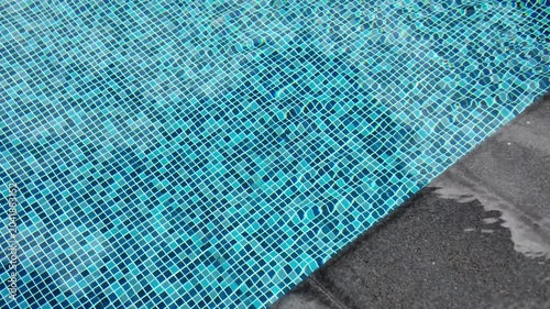 Top view of swimming pool with blue mosaic tiles and water ripples